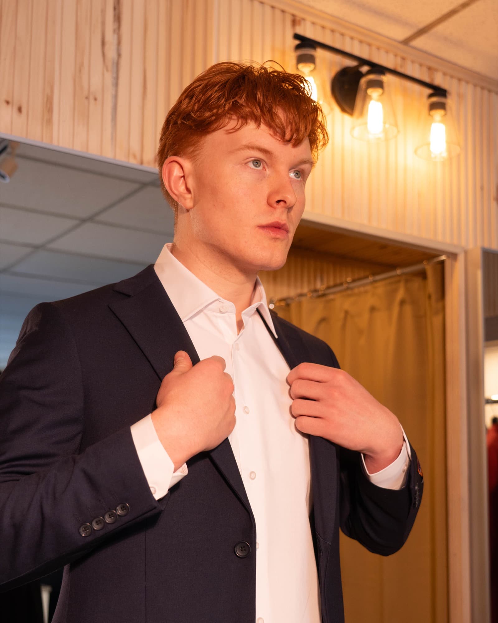 Man adjusting his finished navy suit in the boutique