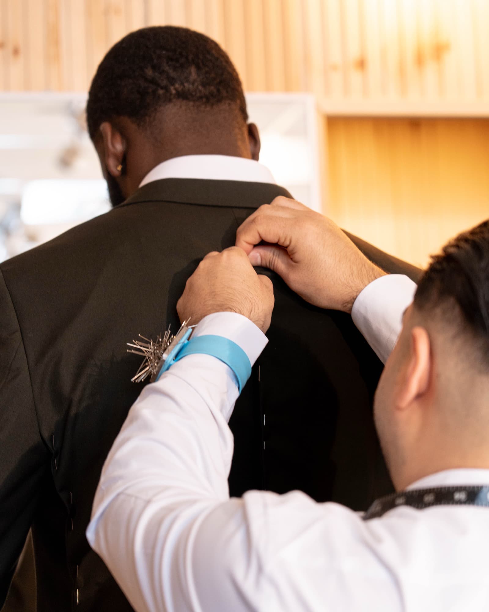 Tailor pinning and adjusting suit on client's shoulder